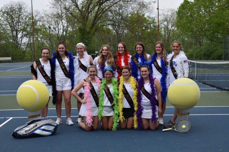The senior girls tennis players huddle with their celebratory sashes and feather boas for a formal picture of the group.