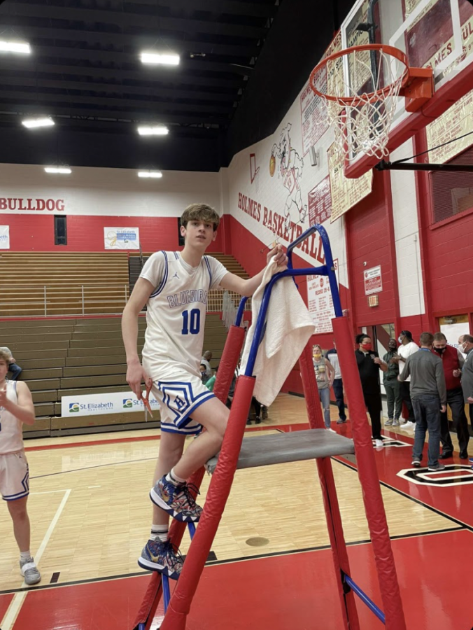 Senior Zach Barth poses as he cuts the net after winning region at Holmes High School.