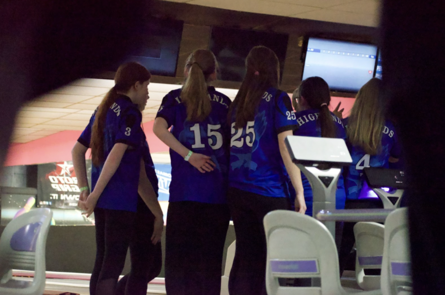 The girls bowling team huddles up, discussing their next strategies. 