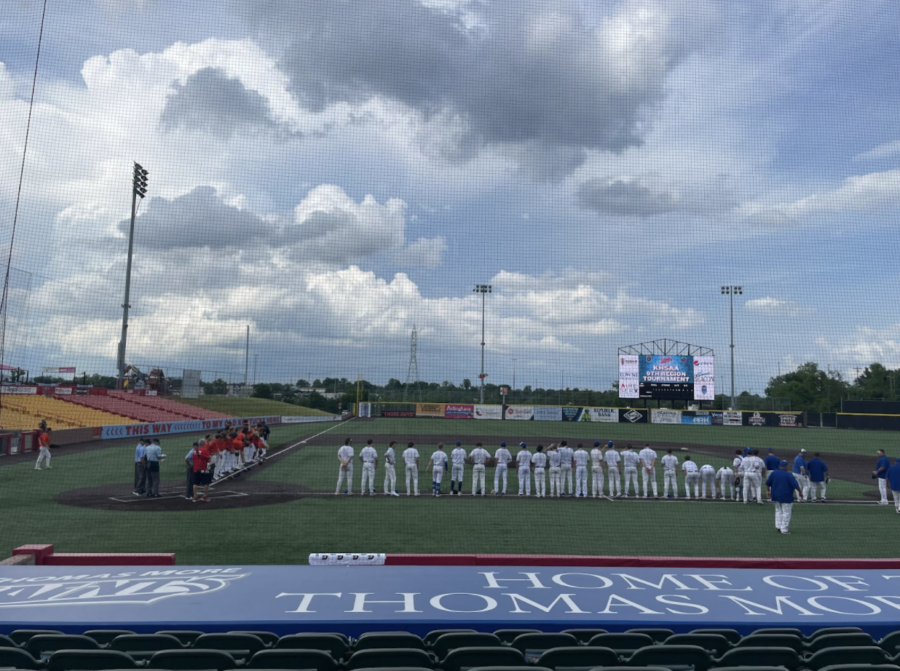 Both varsity baseball teams stand for the National Anthem.