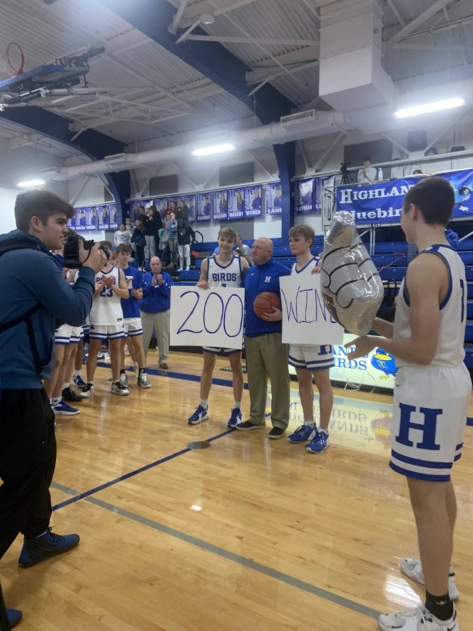 Basketball Coach Kevin Listerman holds up a sign to celebrate the 200th win in his career.
