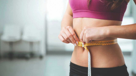 A woman measuring the width of her stomach.