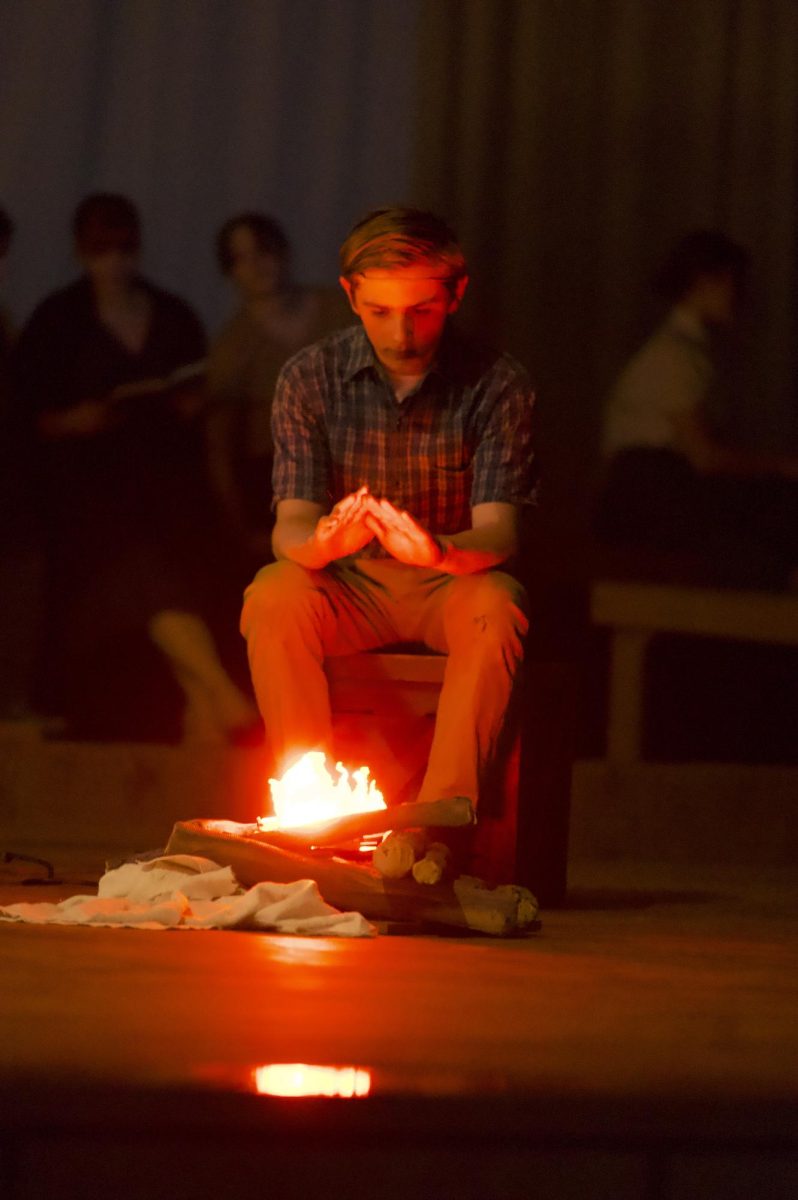 Young Joshua sits in front of a campfire, played by Rafe Pinkston.