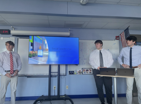In the photo, juniors Josh Hartung, Diego Race, and Hank Shick are giving their business presentation about their experience in a work environment. 