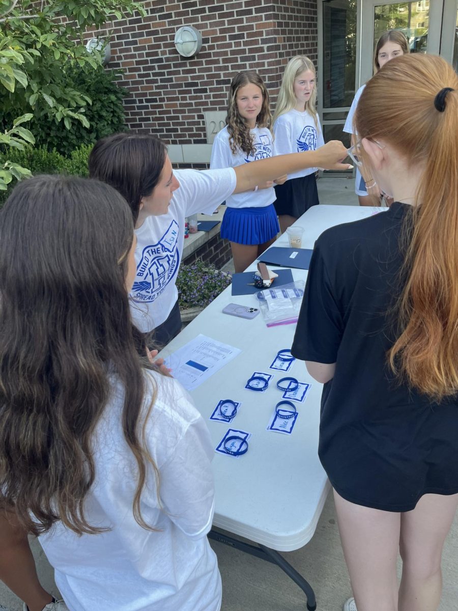 Isa Neufarth (12) points students in the direction of the gym to receive their passports for orientation.