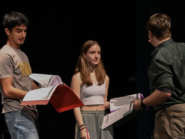 Siddhartha Jani (12), Nellie Albritton (12), and Noah Varland (12) prepare for how they will enter the stage at the start of the scene.