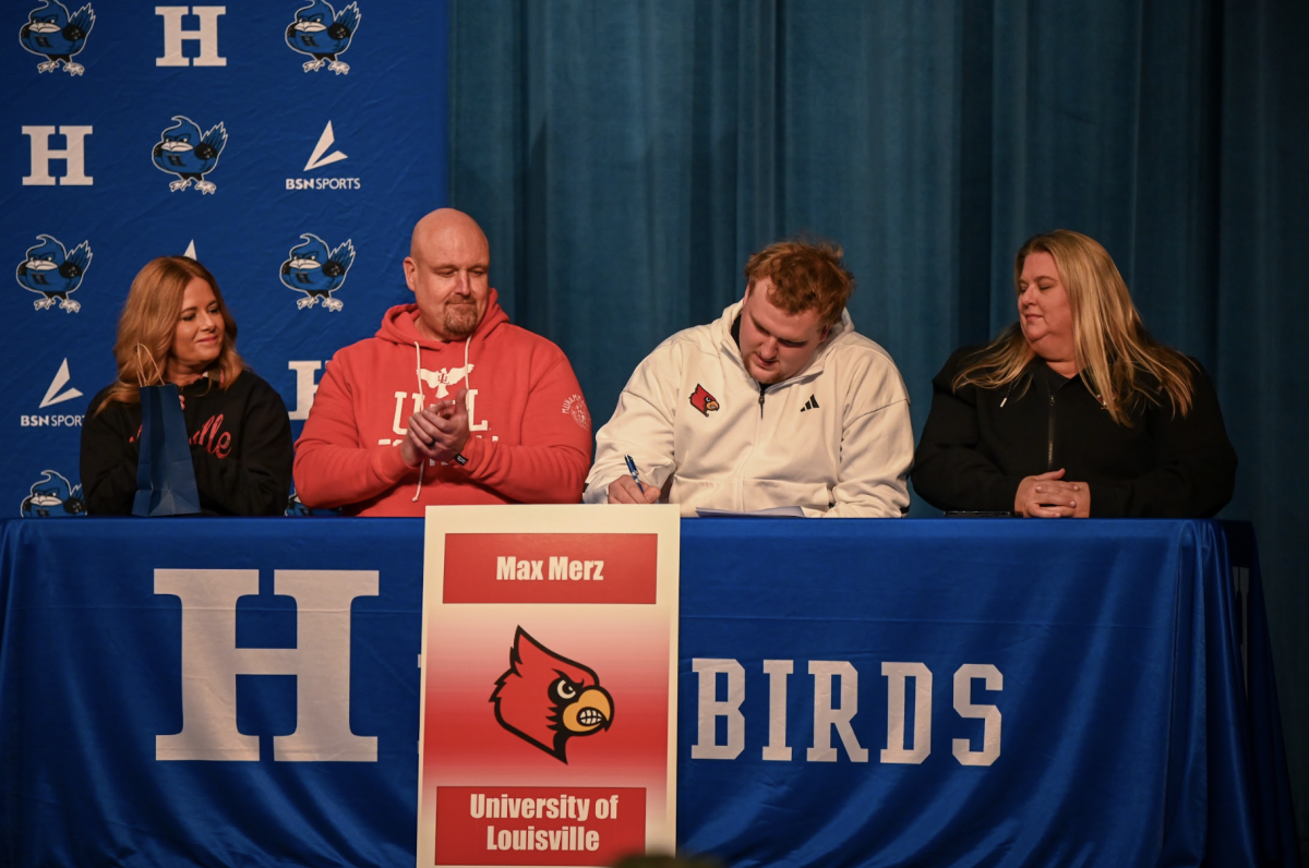 Max Merz (12) sits with his parents and signs to Louisville University for football. 