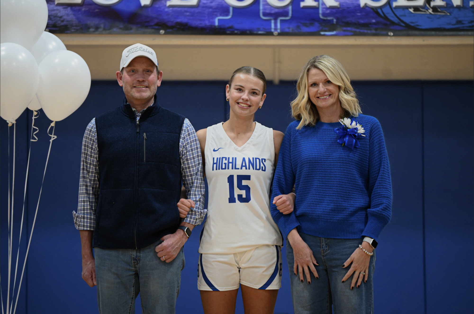 Katie Bucher (12) smiles towards the camera with her parents.