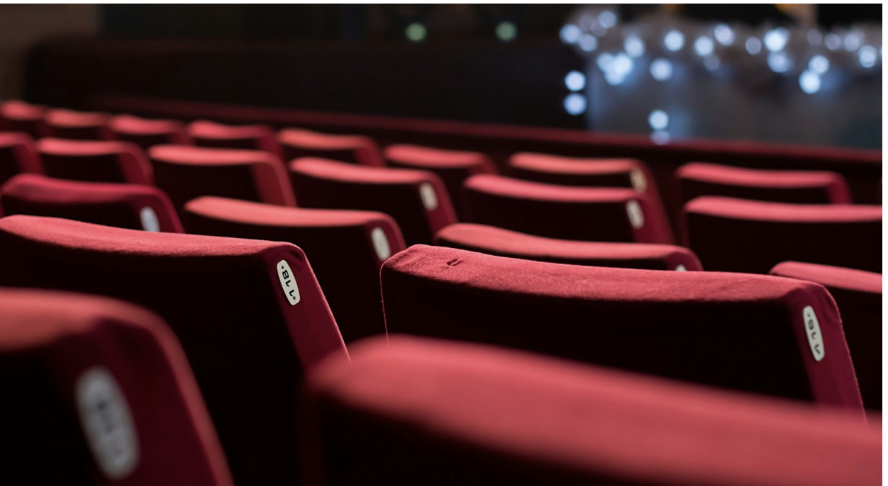 Close up rows of red seats inside an awards venue. (Photo courtesy of Fatma Jarghon, UnSplash)
