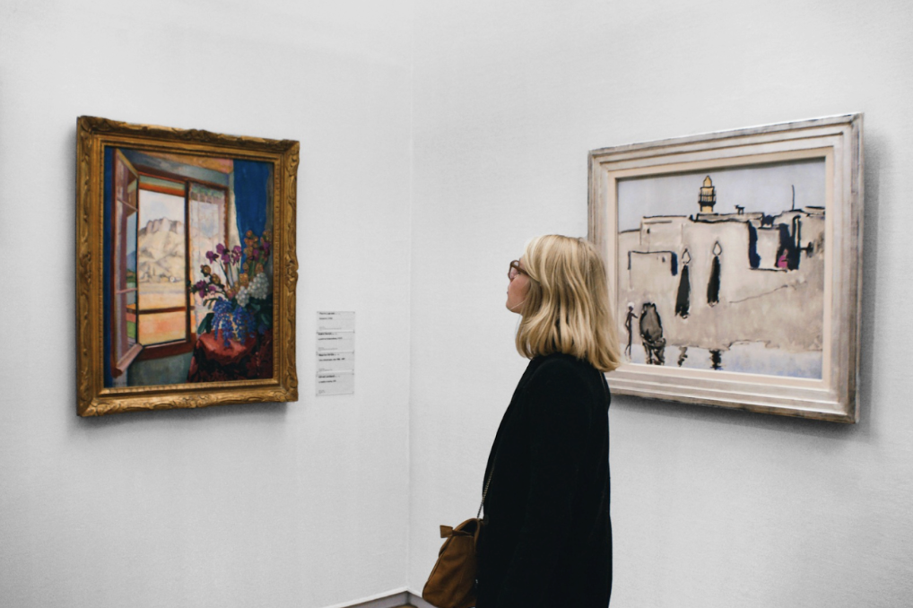 Woman at art gallery views a painting. (Photo Courtesy of Pauline Loroy, Unsplash)
