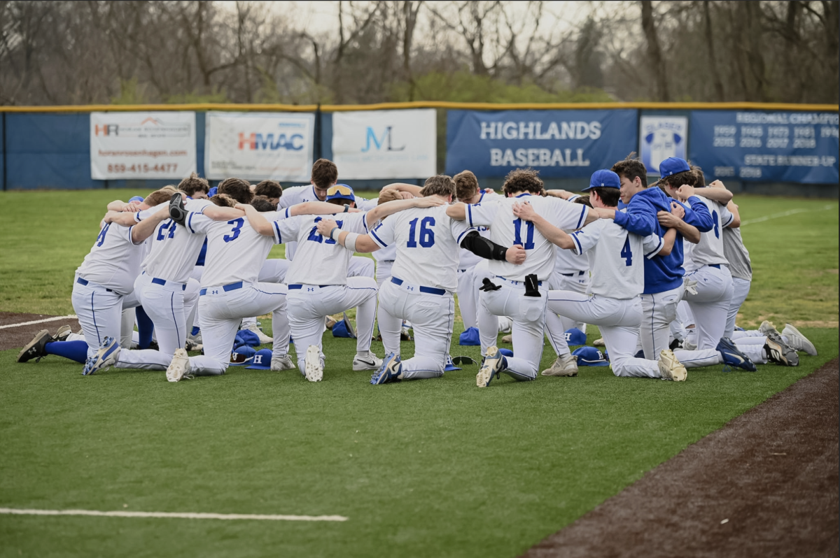 The varsity' boys baseball team prays before the game begins.