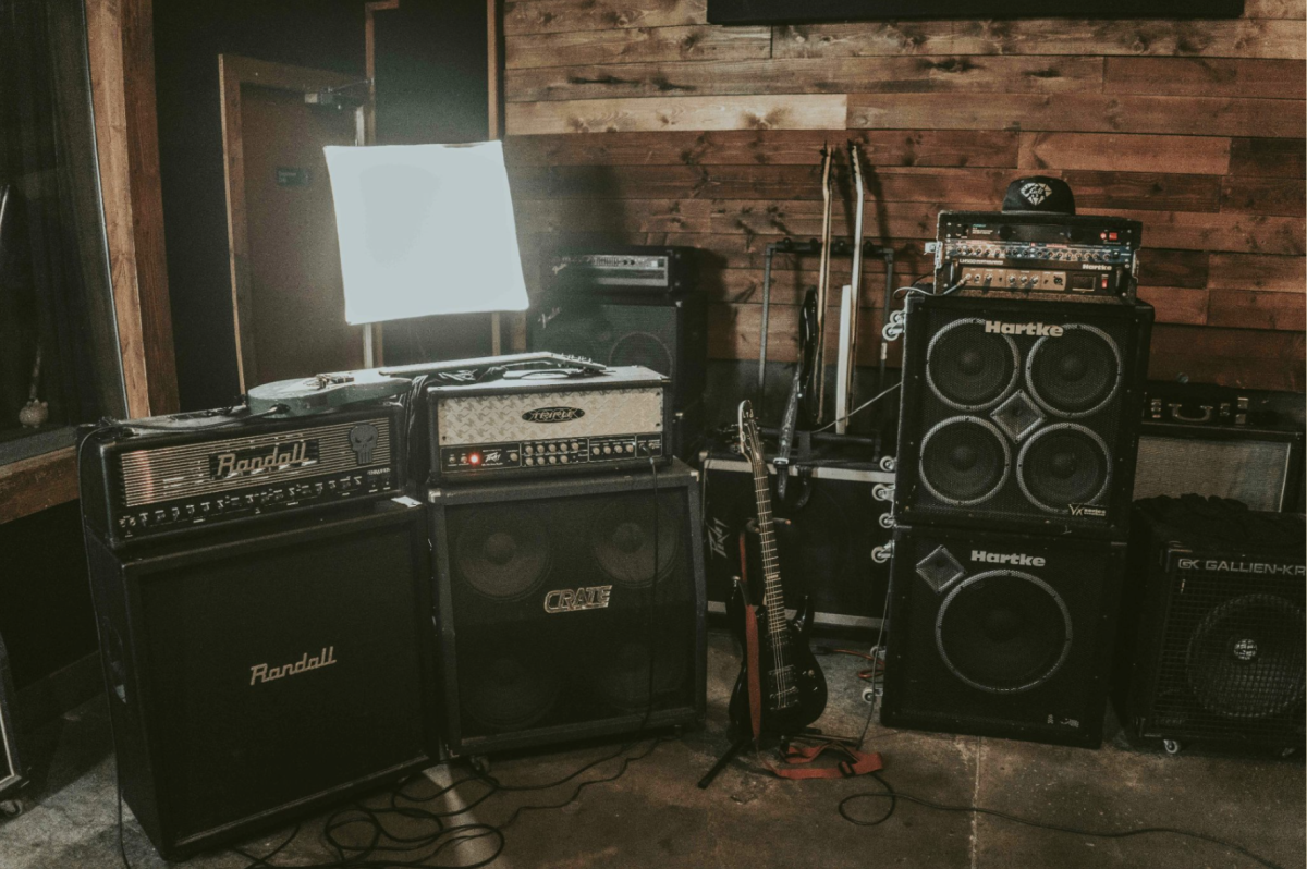 Amps, speakers, lights, and guitar in a bright room. (Courtesy of Krys Amon via Unsplash).