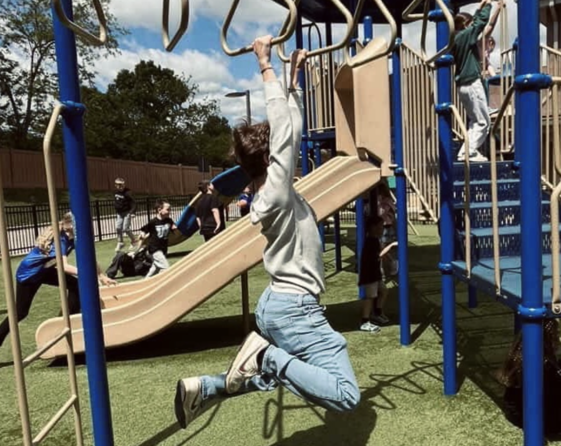 Jonas Foubert (12) hangs from Woodfill Elementary School’s playground while fellow seniors are playing around him. (Kaydin Casebolt, used with permission)
